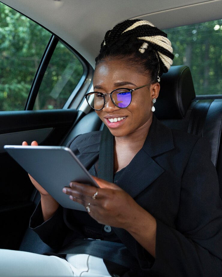 smiley-woman-back-seat-her-car-looking-tablet_23-2148685327